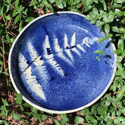 Blue pottery plate with a leaf white leaf pattern in the bottom
