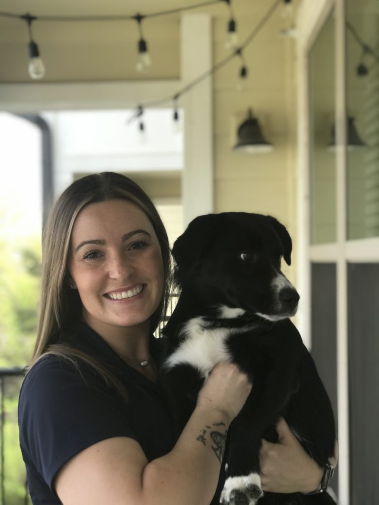 A white woman in her 20's with brown hair holding black and white dog